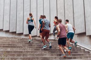 toute la longueur des jeunes en vêtements de sport faisant du jogging tout en faisant de l'exercice dans les escaliers à l'extérieur photo