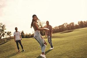 s'apprête à lancer. toute la longueur de jeunes gens souriants en vêtements décontractés jouant au frisbee à l'extérieur photo