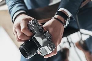 la photographie est sa passion. gros plan d'un jeune homme tenant un appareil photo tout en étant assis sur le tabouret