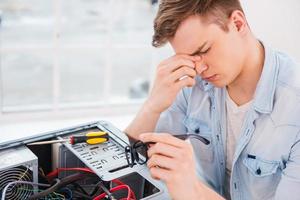 je suis tellement épuisé. vue latérale d'un beau jeune homme touchant son nez avec les doigts et gardant les yeux fermés assis sur son lieu de travail photo