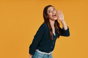 jeune femme espiègle en vêtements décontractés faisant une grimace en se tenant debout sur fond jaune photo