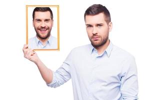 j'avais l'habitude de sourire ... beau jeune homme en chemise tenant une photo de lui-même avec un visage souriant et l'air triste en se tenant debout sur fond blanc