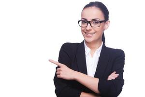 femme d'affaires pointant l'espace de copie. belle jeune femme en tenues de soirée et lunettes pointant vers l'extérieur et souriant tout en se tenant isolé sur blanc photo