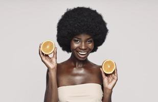 portrait d'une belle jeune femme africaine tenant des morceaux d'orange et souriant photo