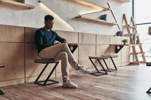 un autre message d'affaires. beau jeune homme utilisant son téléphone intelligent assis dans l'espace de travail créatif photo