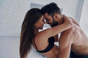 exprimer le véritable amour. beau jeune couple embrassant et souriant assis face à face dans la chambre photo