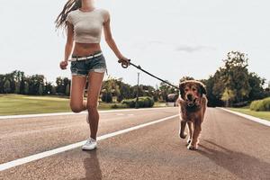 le chien est toujours là. gros plan d'une belle jeune femme jouant avec son chien tout en courant à l'extérieur photo