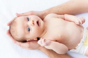 petit bébé curieux. vue de dessus des mains masculines tenant un mignon petit bébé photo