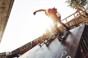 né pour l'embarquement. jeunes hommes modernes faisant du skateboard tout en traînant avec ses amis à l'extérieur photo