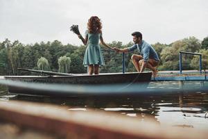 belle journée ensemble. heureux jeune couple se prépare à ramer un bateau tout en profitant de leur rendez-vous à l'extérieur photo