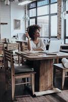 envisager la prochaine étape. réfléchie jeune femme africaine tenant un crayon et regardant ailleurs alors qu'il était assis au restaurant photo