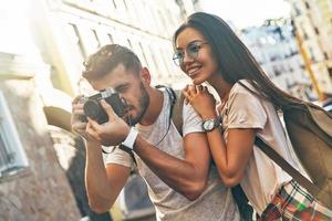 heureux jeune couple photographier quelque chose et souriant tout en se tenant à l'extérieur photo