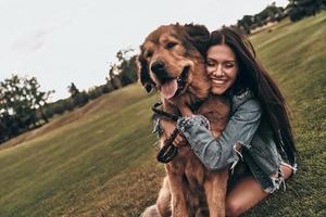 si mignon et adorable. belle jeune femme gardant les yeux fermés et souriant tout en embrassant son chien à l'extérieur photo