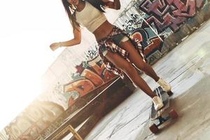 gros plan d'une jeune femme attirante faisant de la planche à roulettes tout en passant du temps au skate park à l'extérieur photo