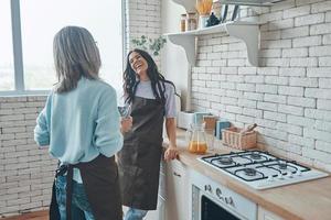 belle jeune femme et sa mère communiquant tout en passant du temps à la cuisine domestique photo