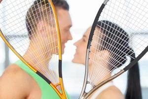 couple de remise en forme. couple d'amoureux s'embrassant derrière une raquette de tennis photo