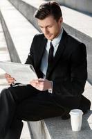 travailler à l'extérieur. jeune homme d'affaires lisant le journal assis dans les escaliers photo