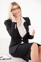 femme d'affaires mature confiante. belle femme d'affaires mûre parlant au téléphone portable et tenant une tasse de café photo