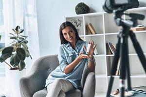 vlogging. jolie jeune femme montrant un produit de beauté tout en réalisant une nouvelle vidéo à l'intérieur photo