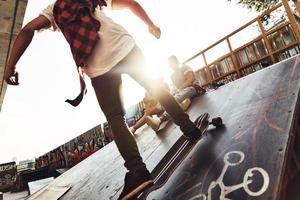 extrême liberté. jeunes hommes modernes faisant du skateboard tout en traînant avec ses amis à l'extérieur photo