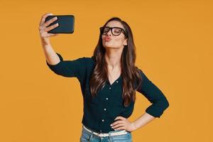 heureuse jeune femme en vêtements décontractés prenant selfie et fronçant photo