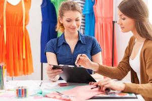 travailler ensemble sur un nouveau look de mode. deux belles créatrices discutant de quelque chose alors qu'elles étaient assises sur le lieu de travail photo