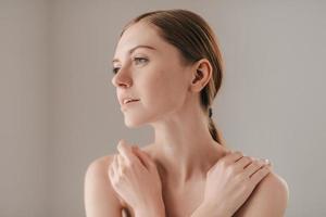 beauté naturelle. jeune femme avec des taches de rousseur sur le visage regardant loin et gardant les mains sur les épaules photo