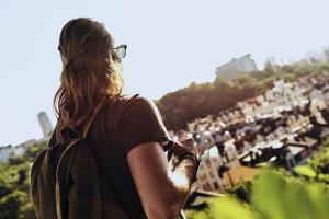 beau jeune homme en vêtements décontractés regardant la vue en se tenant debout sur la colline à l'extérieur photo