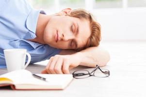 fatigué et surmené. beau jeune homme allongé sur le sol et gardant les yeux fermés photo