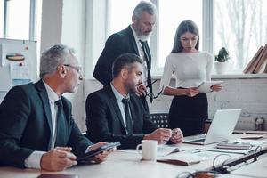 des collègues confiants discutant de la prochaine étape commerciale tout en travaillant ensemble dans le bureau moderne photo