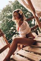beauté sans effort. jolie jeune femme en maillot de bain souriante assise dans la cabane dans les arbres à l'extérieur photo