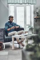 chercher la bonne chanson. beau jeune homme moderne écoutant de la musique assis sur son lieu de travail photo