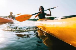 kayak en couple. vue en angle bas d'un beau jeune couple faisant du kayak sur le lac ensemble et souriant photo