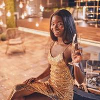 belle jeune femme africaine en robe de soirée tenant une flûte avec champagne et souriant photo