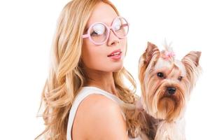 moi et mon chien. Belle jeune femme aux cheveux blonds portant yorkshire terrier dans des vêtements roses et souriant debout isolé sur fond blanc photo