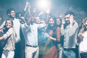 fête sans fin. groupe de beaux jeunes dansant ensemble et ayant l'air heureux photo