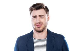 c'est un portrait dégoûtant d'un jeune homme exprimant la négativité et regardant la caméra en se tenant debout sur fond blanc photo