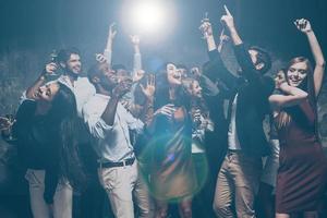 lève les mains en l'air groupe de beaux jeunes dansant ensemble et ayant l'air heureux photo