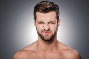 a encore échoué portrait d'un jeune homme torse nu frustré, gardant les yeux fermés en se tenant debout sur fond gris photo