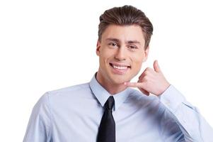 en attente de votre appel beau jeune homme en tenues de soirée gesticulant signe de téléphone et souriant debout isolé sur blanc photo