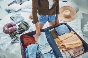 belle jeune femme faisant ses valises assise dans son lit à la maison photo