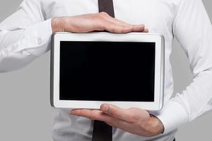 rejoindre une ère numérique. image recadrée d'un homme en tenue de soirée tenant une tablette numérique en se tenant debout sur fond gris photo
