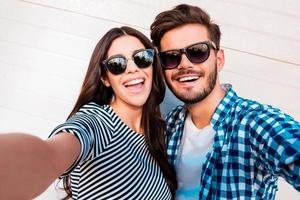 capturer des moments lumineux. joyeux jeune couple d'amoureux faisant selfie devant la caméra tout en se tenant à l'extérieur photo