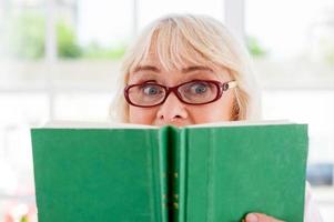 un livre si excitant a surpris une femme âgée tenant un livre et regardant par là photo