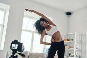 belle jeune femme africaine qui s'étire et sourit tout en faisant une vidéo sur les réseaux sociaux photo