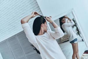 toujours à la mode. jolie jeune femme essayant un bandana debout près du miroir à la maison photo