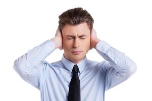 malade et fatigué. jeune homme frustré en chemise et cravate couvrant les oreilles avec les mains et gardant les yeux fermés tout en se tenant isolé sur blanc photo