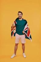 toute la longueur du beau jeune homme en vêtements décontractés portant le drapeau britannique photo