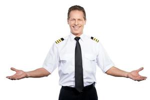 bienvenue à bord heureux pilote masculin en uniforme gesticulant et souriant en se tenant debout sur fond blanc photo