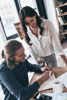 passer en revue les détails. vue de dessus de jeunes collègues modernes en vêtements décontractés intelligents travaillant ensemble et souriant tout en passant du temps dans le bureau de création photo